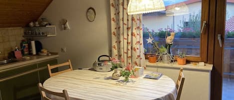 Un comedor con una mesa redonda, sillas, un radio y plantas en macetas.