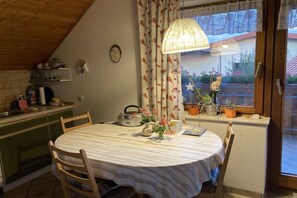 A dining area with a round table, chairs, a radio, and potted plants. - Holiday apartment with 1 bedroom (Bodolz)