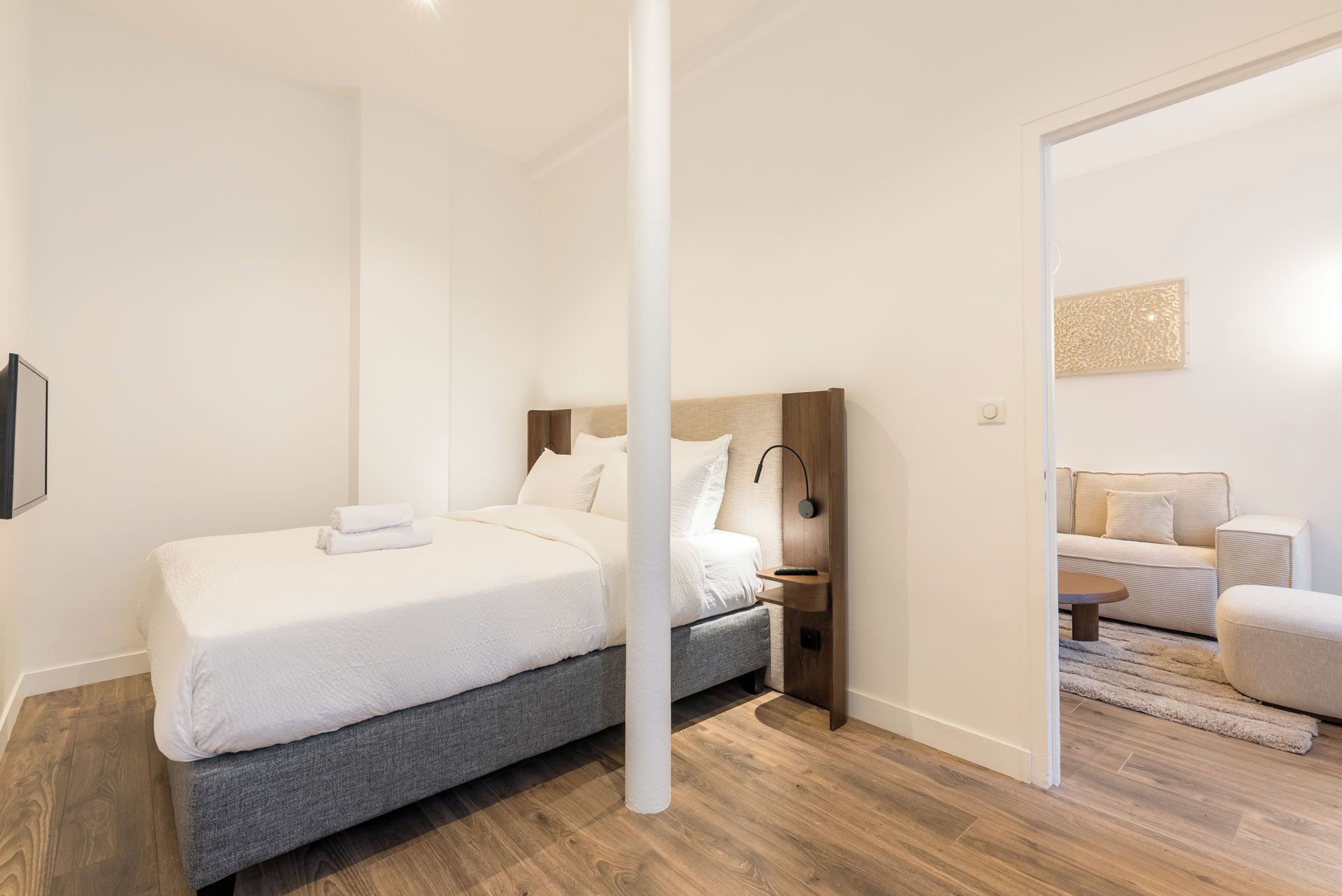 Un dormitorio moderno con cama, mesita de noche y vistas a otra habitación.