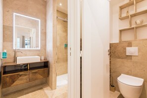 A modern bathroom with a large mirror, a sink, a toilet, and a shower area. - Elégant appartement près du Moulin Rouge (Paris)