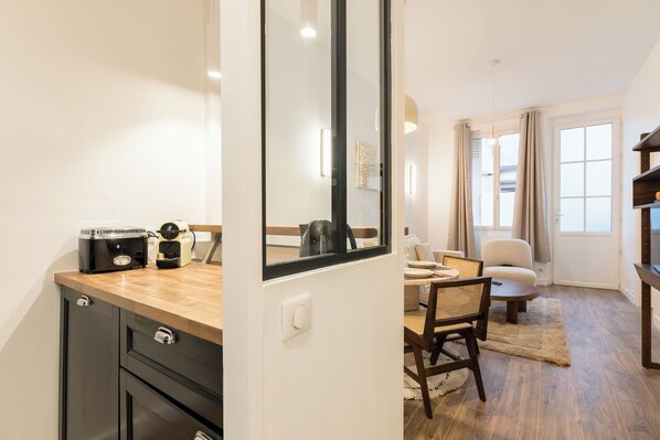 A compact living space with a kitchenette, dining area, and a large mirror reflecting the room. - Elégant appartement près du Moulin Rouge (Paris)
