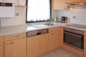 A modern kitchen with a stainless steel sink, a built-in oven, and wooden cabinets. - Holiday home in Allgäu with 1 bedroom (Lechbruck)