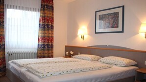 Ein Hotelzimmer mit einem Doppelbett, zwei Nachttischlampen, einem gerahmten Bild an der Wand und einem Heizkörper.