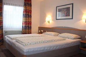 Quarto de hotel com cama de casal, duas luminárias de cabeceira, um quadro na parede e um radiador.