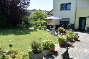 Ein Innenhof mit Rasenfläche, Blumentöpfen, Gartenmöbeln und einem Gebäude mit einer Garagentür.
