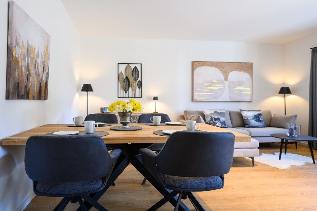 Un salon moderne avec un coin repas, comprenant un canapé, des fauteuils, une table basse et des œuvres d’art accrochées aux murs.