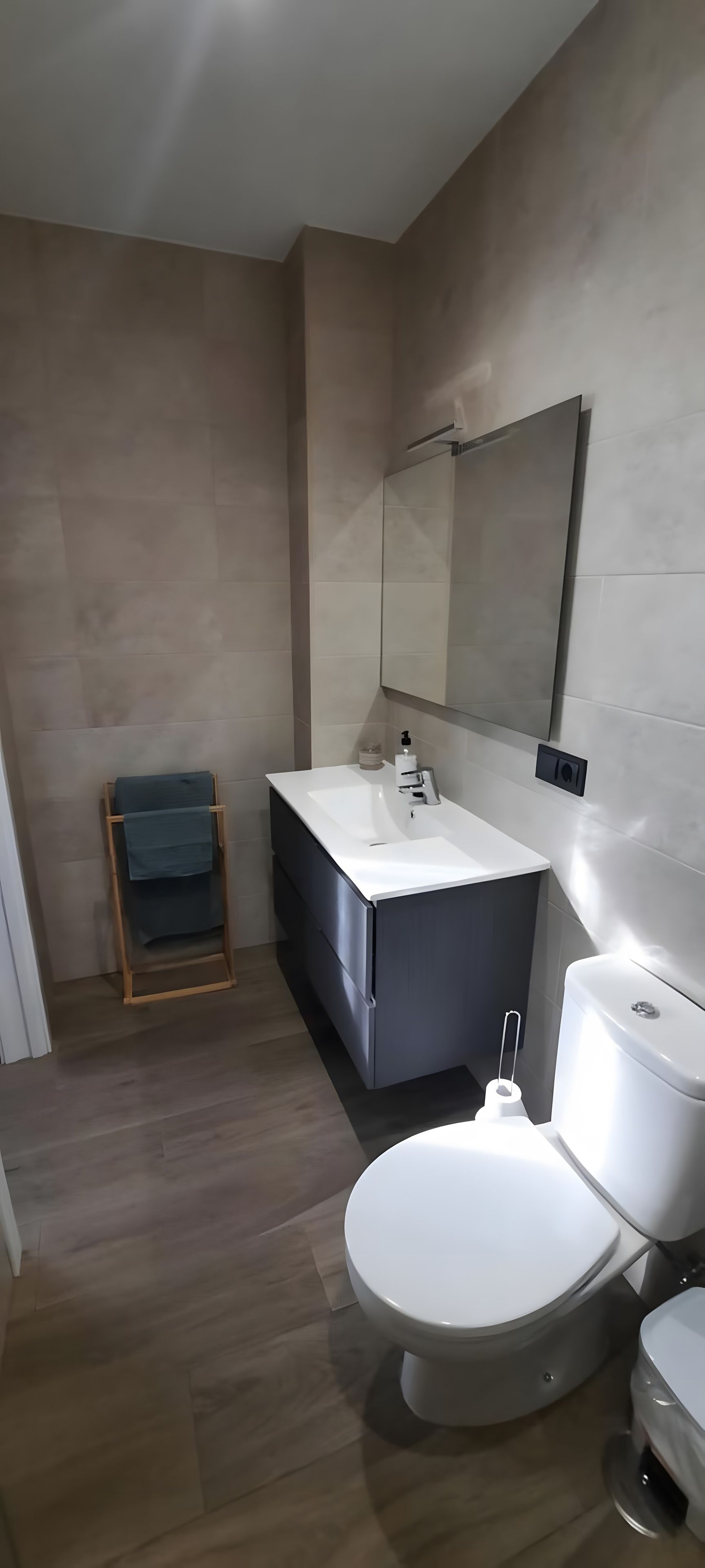 A modern bathroom with a white sink, dark vanity, and a toilet.