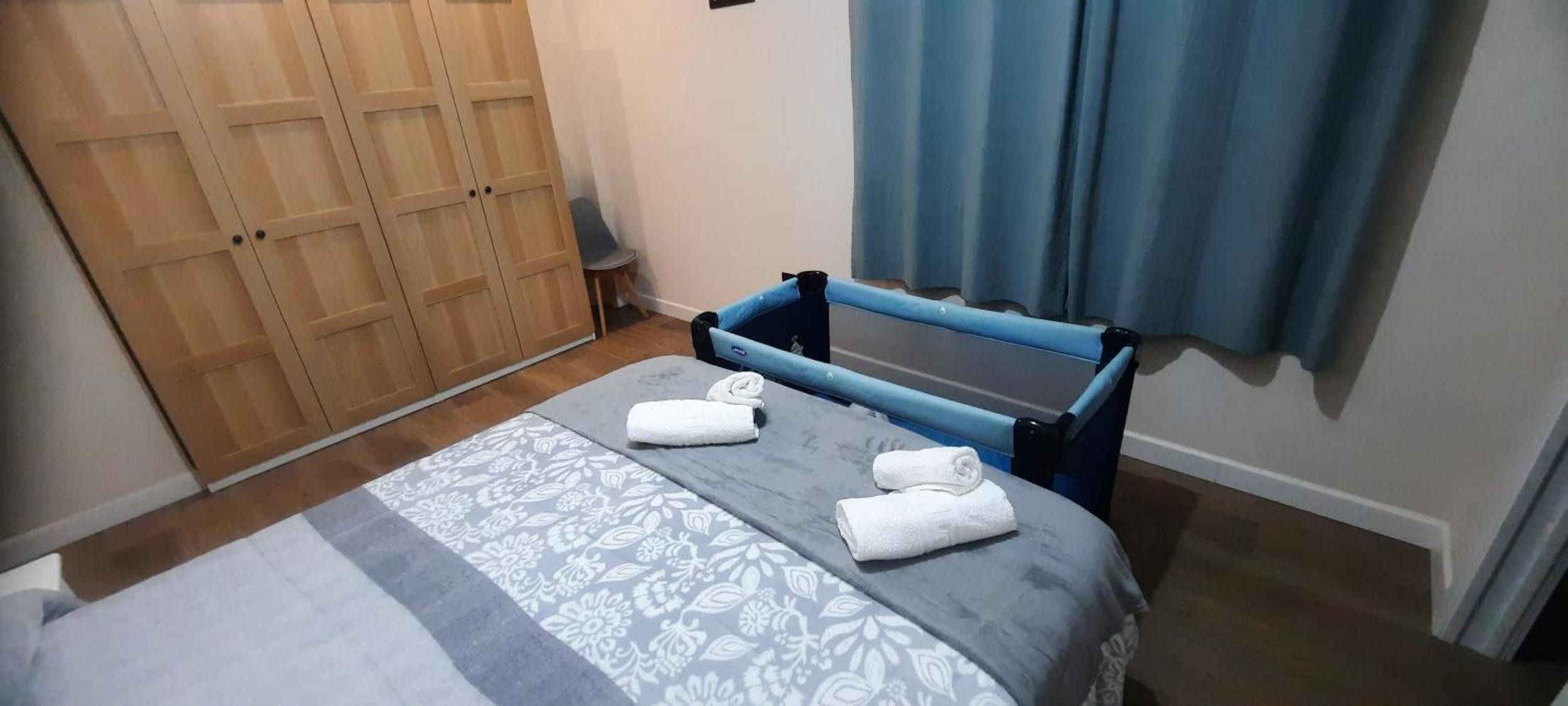 Ein Schlafzimmer mit einem Bett, einem Kleiderschrank und einem fenster mit Vorhängen.
