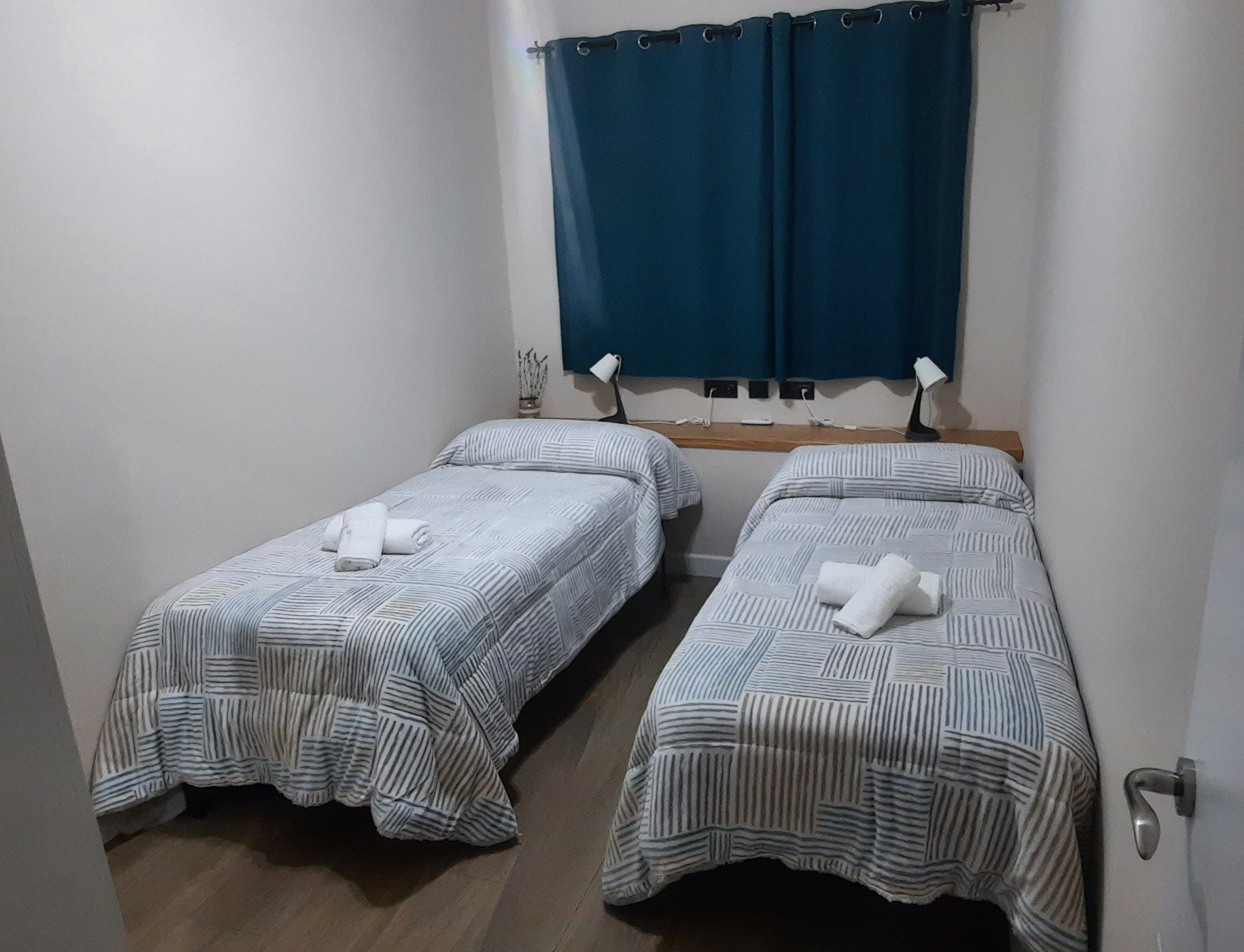Una habitación con dos camas individuales, cada una con una colcha a rayas y una toalla enrollada.
