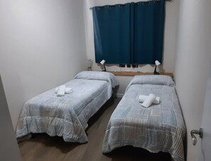 Habitació amb dos llits individuals, cadascun amb estriat i una tovallola enrotllada.