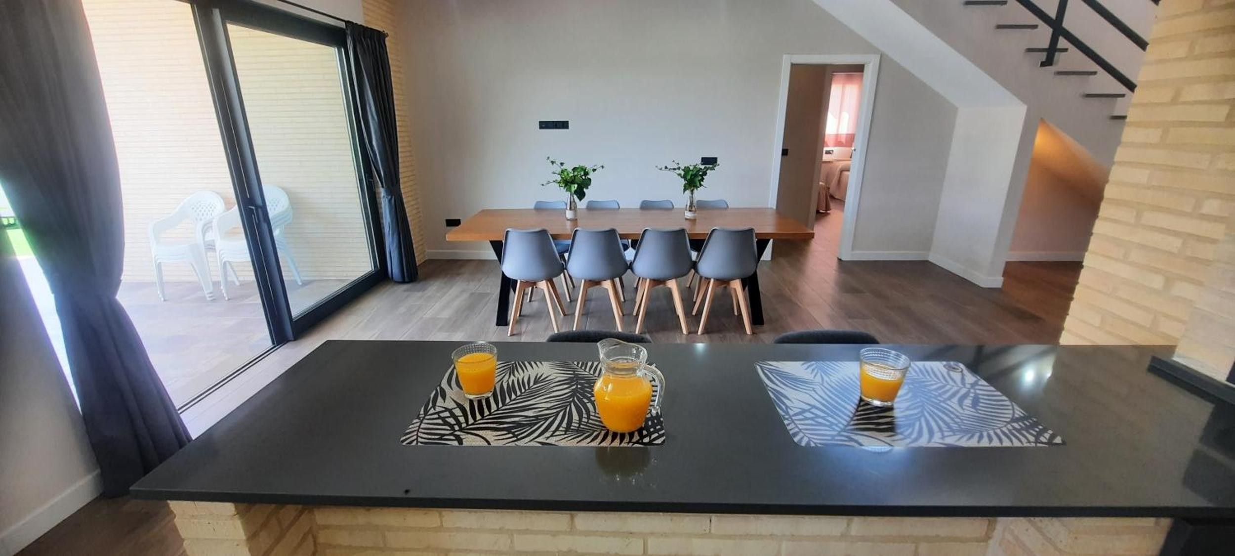Cocina moderna con comedor, que incluye una isla grande con dos individuales, un vaso de zumo de naranja y una jarra.