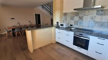 A modern kitchen with a central island, white cabinetry, and a stainless steel range hood.