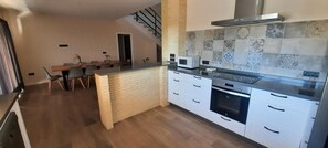 A modern kitchen with a central island, white cabinetry, and a stainless steel range hood.