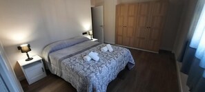 A hotel room with a bed, bedside lamps, a wardrobe, and a mirror.