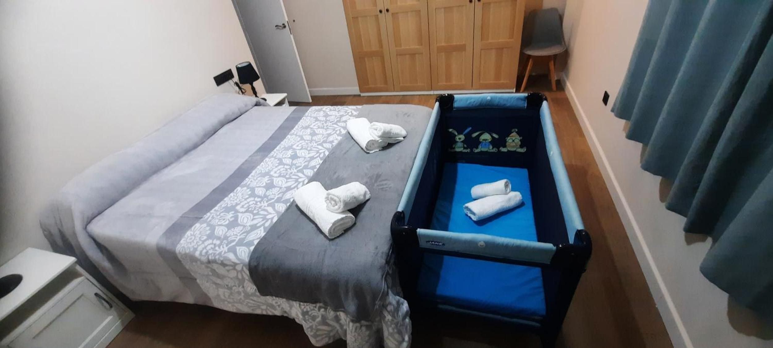 Een slaapkamer met een bed, een tafeltje, een stoel en een kledingkast.