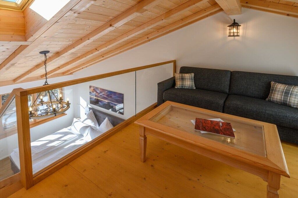 Une pièce de style « loft », avec un plafond en bois, une table en verre, un canapé et un luminaire suspendu.