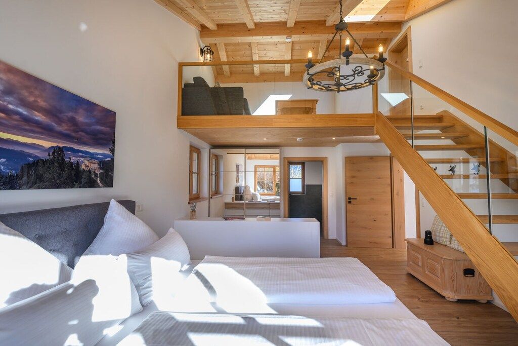 Ein Schlafzimmer mit einem großen Bett, einem erhöhten Bereich und einer Treppe.