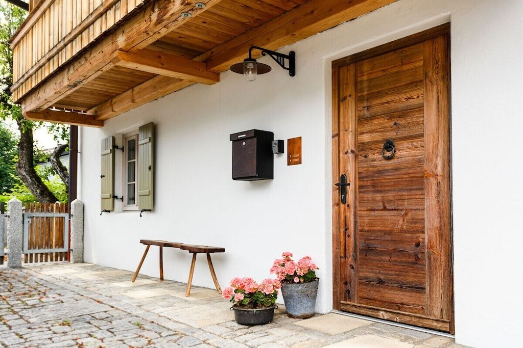 Une porte en bois, un banc et des plantes en pot devant un bâtiment.