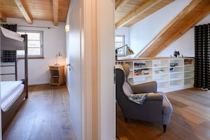 A loft bedroom with a bunk bed, a desk, and a chair. There is a sloped ceiling and a bookshelf. - Alpenkönig II in the Alpenkönig House (Garmisch-Partenkirchen)