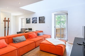 A modern living room with a sofa set, a desk with a computer, and a view through a glass door. - Alpenkönig II in the Alpenkönig House (Garmisch-Partenkirchen)