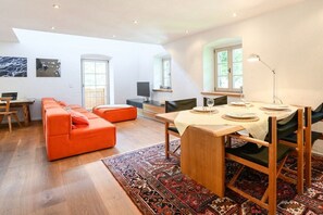 A modern living room with a sofa, a dining table set for four, and a television. - Alpenkönig II in the Alpenkönig House (Garmisch-Partenkirchen)