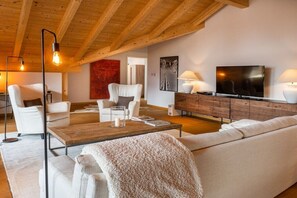 Ein modernes Wohnzimmer mit Holzboden, einer Couch, einem Couchtisch und einem Fernseher.