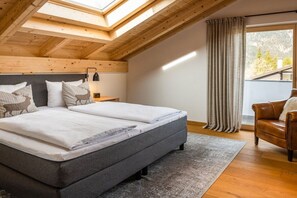Une chambre avec un grand lit, une table de chevet, une lampe, une fenêtre avec des rideaux et une vue sur l’extérieur.