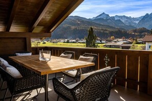 Une terrasse en bois avec une table et des chaises, offrant une vue sur un paysage montagneux.