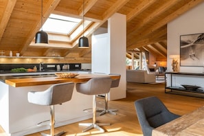 A modern kitchen with a central island, bar stools, and pendant lighting. - Holiday apartment with 3 bedrooms (Garmisch-Partenkirchen)