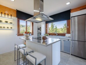 A modern kitchen with a central island, stainless steel appliances, and a view of the outdoors. - Villa with private pool in Mancor de la Vall (Mancor de la Vall)