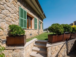 Ein Gebäude aus Stein mit grünen Fensterläden, einer Treppe und Topfpflanzen.