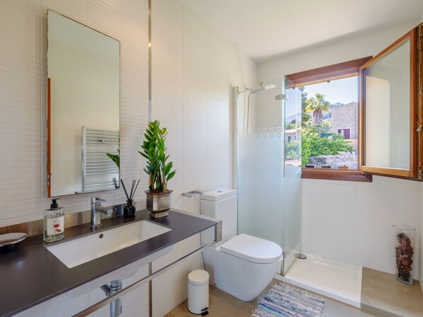 Ein modernes Badezimmer mit großem Spiegel, Waschbecken, Toilette und Dusche.