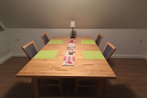 A rectangular dining table with four chairs, a table runner, and a floor lamp. - Holiday apartment with 2 bedrooms (Warendorf)