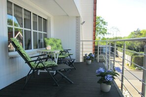 A covered outdoor area with a table and chairs, a railing, and potted plants. - Holiday apartment with 2 bedrooms (Warendorf)