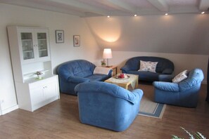 A living room with two blue armchairs, a white cabinet, and a small table with a lamp. - Holiday apartment with 2 bedrooms (Warendorf)