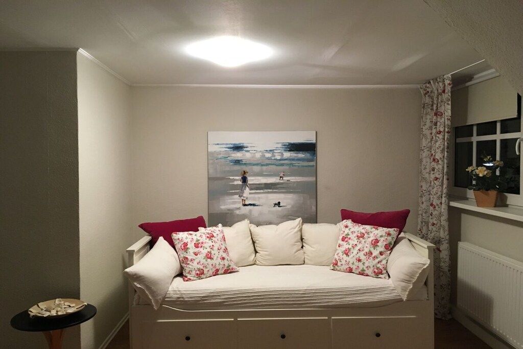 Ein Schlafzimmer mit einem Bett, einem Bild an der Wand, einem Fenster mit Vorhängen und einer Heizung.