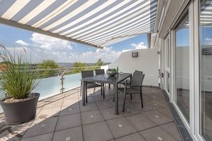 Eine Terrasse mit Tisch und Stühlen, einem Blumentopf und Blick aufs Meer.