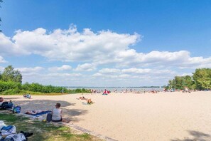A beach with people sunbathing and swimming, a clear sky, and a calm sea. - Holiday apartment with 1 bedroom (Wunstorf Steinhude)