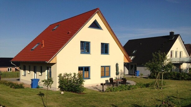 A residential house with a red roof, a front porch, and a well-maintained lawn. - B - Holiday home Katharina (Wohlenberg)