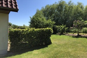 A well-maintained garden with a hedge, a lawn, and a variety of trees. - B - Holiday home Katharina (Wohlenberg)