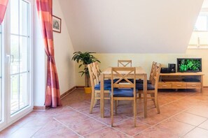 Een eethoek met een tafel, stoelen, een televisie en een potplant.