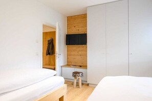Une chambre avec deux lits, une armoire en bois et un petit tabouret.