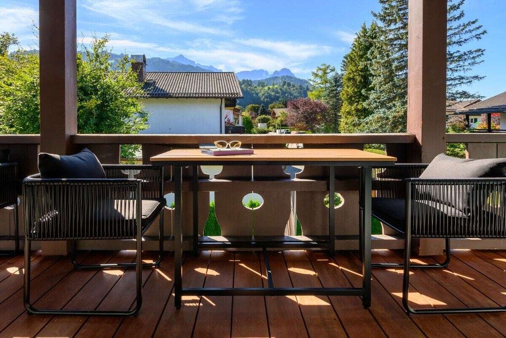 Eine Holzterrasse mit Tisch und Stühlen mit Blick auf eine Berglandschaft.