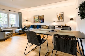 A modern living room with a sofa, chairs, a dining table, and artwork on the walls.
