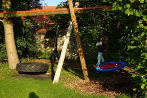 A swing set with a tire swing and a tire swing attached to a wooden structure. - at the Feneberg holiday farm (Eggenthal)