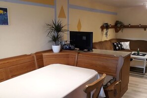 A living room with a wooden bench, a television, a potted plant, and a sofa with cushions. - at the Feneberg holiday farm (Eggenthal)