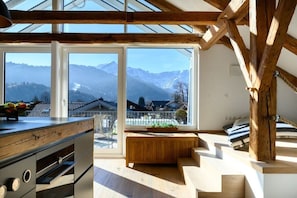 A modern kitchen with large windows, wooden beams, and a view of mountains. - Holiday apartment with 2 bedrooms (Garmisch-Partenkirchen)