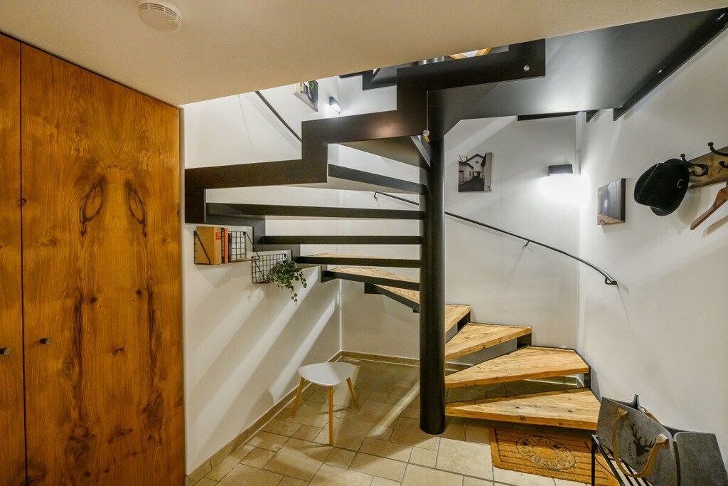 A modern interior with a spiral staircase, wooden flooring, and a minimalist design.