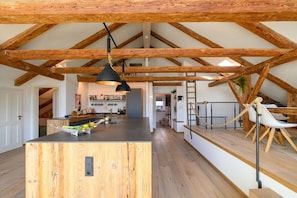 A spacious kitchen with a central island, wooden beams, and a hanging light fixture. - Holiday apartment with 2 bedrooms (Garmisch-Partenkirchen)