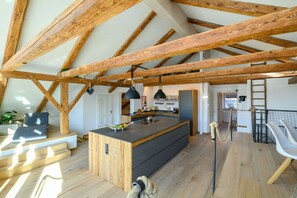 Un loft spacieux avec des poutres apparentes, un îlot central dans la cuisine et un coin salon confortable.